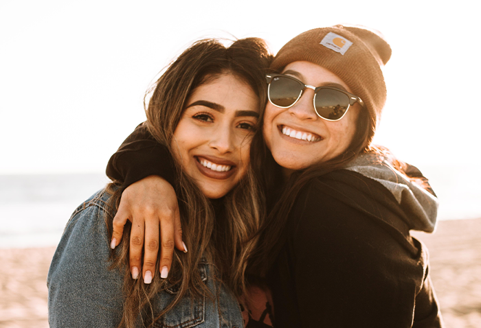 Photo of two women smiling with their arms around each other. Photo by Omar Lopez. Featured image for blog titled: 5 Red Flags When The Woman You Love Is Best Friends With An Ex